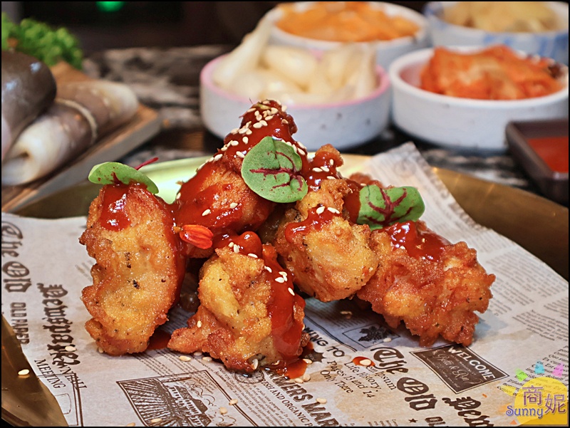 鰻鰻烤韓式炸雞，外皮酥脆、肉質多汁，淋上甜辣醬汁並撒上芝麻與香草，視覺與味覺兼具。